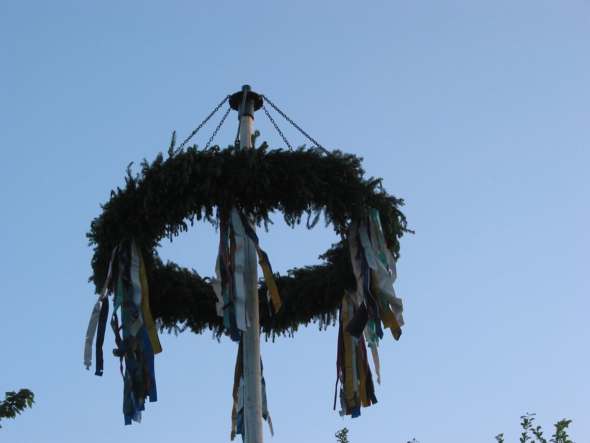 Maibaum mit geschmücktem Kranz und bunten Bändern beim Maifest in Sende